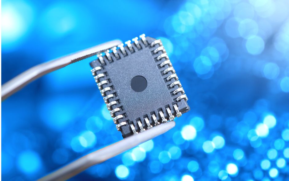 Close-up photo of a microchip being held by a tweezer, revealing intricate circuitry. The background is a blurred blue with illuminated dots, creating a captivating visual effect