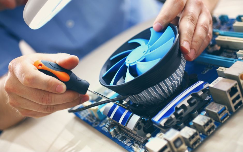 Person repairing a blue computer fan with a screwdriver, ensuring optimal performance and cooling efficiency